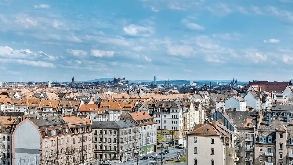 Das Bild zeigt den Panorama-Blick auf die Dächer der Stadt Nürnberg. Am Horizont ist die Nürberger Burg zu sehen.